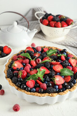 Sweet tart with different fresh berries and mint on white background, closeup