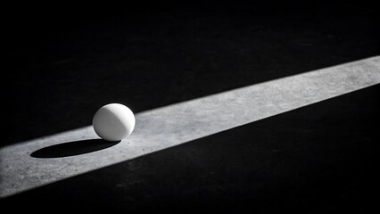 Single white ball with dramatic shadow and light in dark background 
