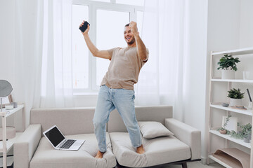 Happy man celebrating while working from home, embracing emotional minimalism and soft masculinity...