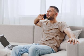 A relaxed man talking on the phone while sitting comfortably on a couch, symbolizing the blend of...
