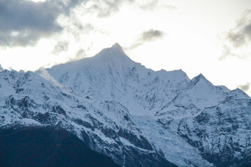Fototapeta premium Jagged, snowy peaks loom under a cloudy sky Meili Snow Mountain Yala Snow Mountain, Sichuan, China