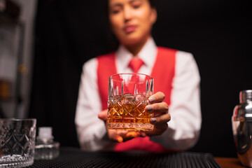 Bartender woman pours whiskey into a glass in a restaurant.	