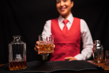  Bartender woman pours whiskey into a glass in a restaurant.