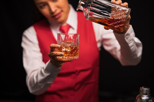 Bartender woman pours whiskey into a glass in a restaurant.	 - Powered by Adobe