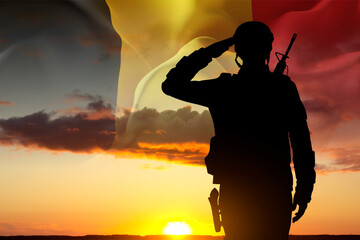 Silhouette of a saluting soldier against the sunset with Belgium flag. National Holidays concept