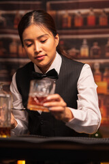 Bartender woman pours whiskey into a glass in a restaurant.	
