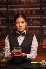 Bartender woman pours whiskey into a glass in a restaurant.	
