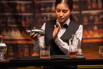  Bartender woman pours whiskey into a glass in a restaurant.