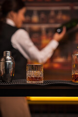  Bartender woman pours whiskey into a glass in a restaurant.