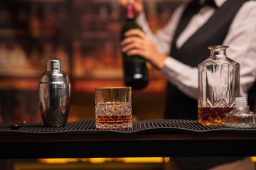 Bartender woman pours whiskey into a glass in a restaurant.	
