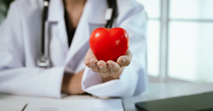 Red heart in female doctor's hand. Concept of health or repair and support. International Heart Day. Doctors Day. World Health Day. - Powered by Adobe