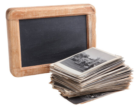 Vintage photos and a wooden slate.  A stack of old black and white photographs sits below a vintage wooden-framed slate board