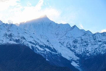 Fototapeta premium Jagged, snowy peaks loom under a cloudy sky Yala Snow Mountain, Sichuan, China