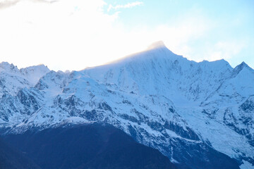 Fototapeta premium Jagged, snowy peaks loom under a cloudy sky Yala Snow Mountain, Sichuan, China