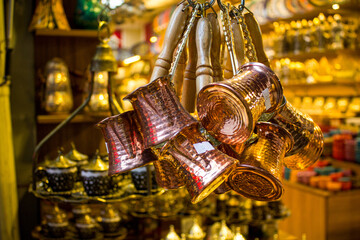 Hanging copper or brass cezves(turks)that reflect the light.They have a conical shape and a...