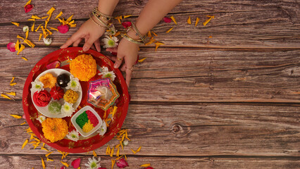 Diwali celebration. Hands arranging traditional decorative plate with flowers and sweets.