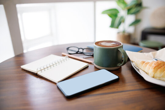 coffee drink and mobile phone, open note book for taking note with breakfast