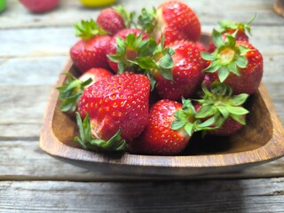 juicy ripe strawberries lie in a wooden plate
