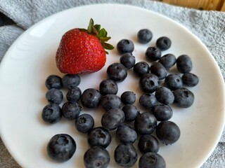 Fresh strawberries, blueberries, and raspberries on white plate