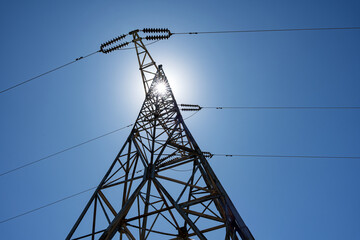 High voltage electricity tower and power lines under the blue sky. Electricity pylons and lines on a clear blue sky. View of a power transmission tower. View from below.
