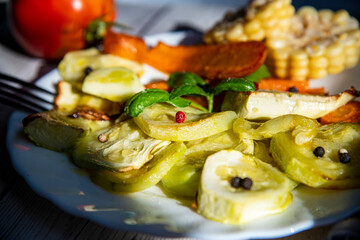 Baked zucchini slices served on a white plate with fresh basil garnish.