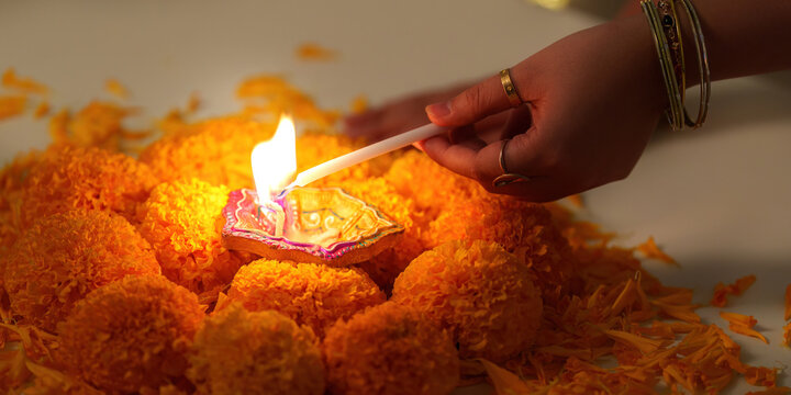 Diwali Celebration. Lighting a traditional oil lamp surrounded by marigold flowers.