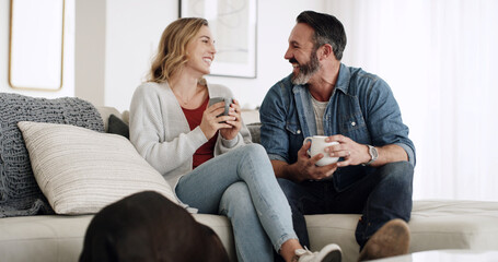 Coffee, laughing and love with couple on sofa in living room of home together for break or...