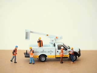 Mini toy of action figure at table with blurred background. Industrial business photography concept design. Minifigure of engineer character with crane truck at site plant.