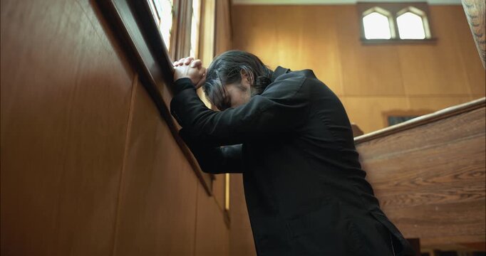 A Christian man, priest, preacher, pastor praying on his knees inside an old church.