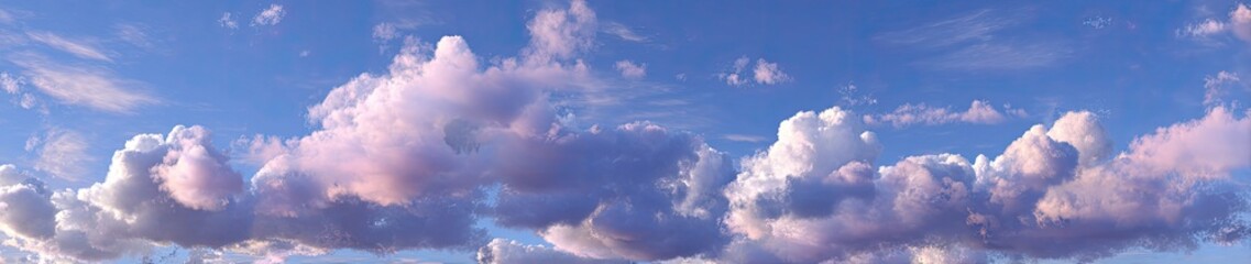 Pastel-hued clouds drift across a vast expanse of vibrant blue sky