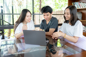 A Group of Asian male and female students arranged a meeting, using a laptop as a tool to share valuable knowledge and build strategies that can guide their successful future together.