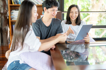 A Group of 3 Asian students collaborates in the university library, tutoring intensively, reading important resources, and depending on a laptop to enhance their overall study performance.