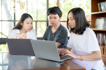During teamwork, 3 Asian students engage in a project, using a laptop to integrate education...