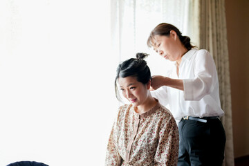 A woman is getting her hair done by another woman. The woman getting her hair done is wearing a...