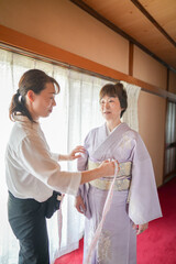 Fototapeta premium A woman is getting her dress measured by another woman. The woman in the dress is wearing a kimono