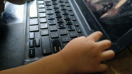Child's Hand Interacting with Laptop Keyboard and Screen Reflection