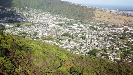 Manao suburb district with minder houses and homes surrounded by green mountains. Aerial top down shot. Honolulu city on Hawaii, USA. Sunny summer day. Peaceful cityscape neighborhood.