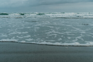 Calm Ocean Waves Gently Washing Ashore on a Cloudy Day.