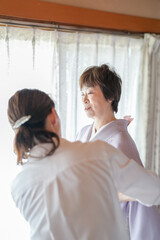 Obraz premium A woman in a white shirt is assisting another woman in a purple robe