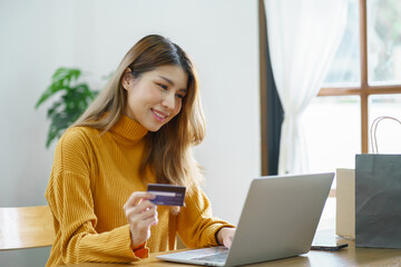 Woman shopping on laptop holding credit card for Internet online e-commerce shopping spending...