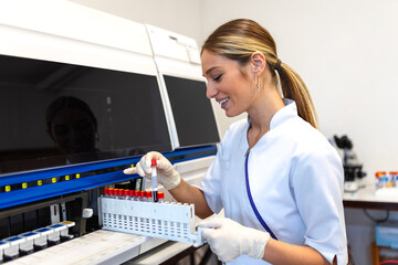 Lab tech loading samples into a chemistry analyzer. female lab tech loading specimen for...