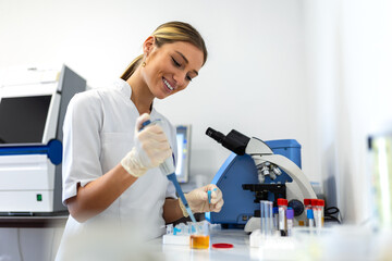 Portrait of female scientist with a pipette analyzes a liquid to extract the DNA and molecules in the test tubes in laboratory. Concept of research,biochemistry, pharmaceutical medicine