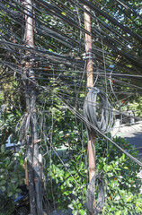 Electric poles with convoluted and chaotic electrical and telephone network cable installations are...