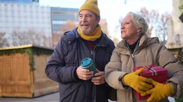 Happy senior couple enjoying christmas time at city market - Powered by Adobe