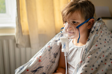 The child girl making inhalation with nebulizer to reduce coughing. Cold and flu, bronchitis,...