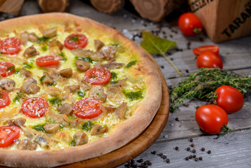 pizza with meat, cherry tomatoes and herbs on a board 