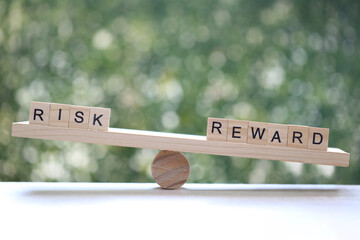 Wording risk and reward on wood block on natural green background, Business investment and Risk management concept.Financial risk assessment
