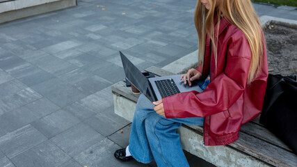 Woman working on a laptop outdoors.