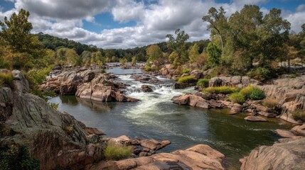 Obraz premium River flows through rocky terrain with trees under a cloudy sky.
