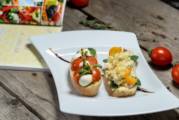 Bruschetta with tomatoes and kami spreads in a white plate on a wooden background